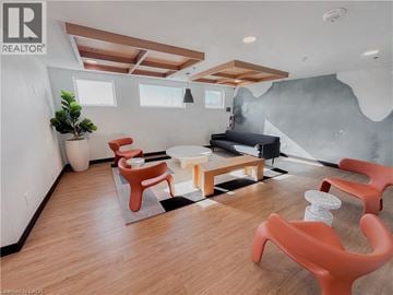 Kitchener condo for rent - A living room with orange chairs and a black couch.