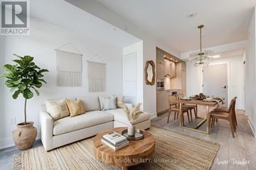 Toronto (Dovercourt-Wallace Emerson-Junction) condo for rent - A living room with a white couch, a wooden coffee table, and a dining table with chairs.