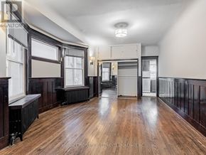 Toronto (Palmerston-Little Italy) apartment for rent - A spacious room with wooden floors and a central heating unit.