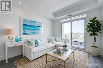 Toronto (Dovercourt-Wallace Emerson-Junction) condo for rent - A living room with a white couch, a painting on the wall, and a plant on the side table.