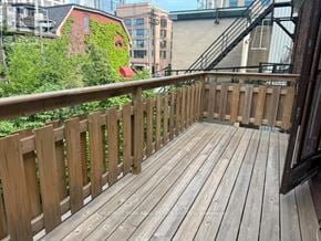 Toronto (Annex) apartment for rent - A wooden deck with a railing and a building with a red door in the background.