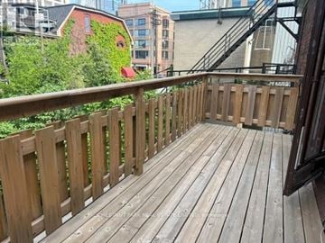 Toronto (Annex) apartment for rent - A wooden deck with a railing and a building with a red door in the background.