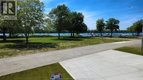 Amherstburg townhouse for rent - A realtor sign is in front of a grassy area with a lake in the background.
