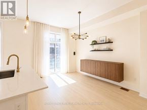 Richmond Hill townhouse for rent - A modern kitchen with a sink, a window with curtains, and a wooden cabinet.