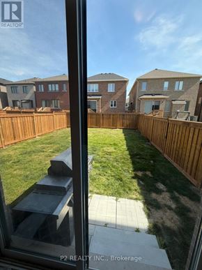 Barrie apartment for rent - A view from a window looking out at a backyard with a wooden fence and houses in the background.