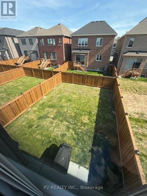 Barrie apartment for rent - A backyard with a wooden fence and a grassy area.