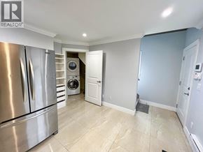 Vancouver apartment for rent - A kitchen with a stainless steel refrigerator and a washing machine in the corner.
