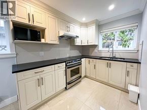 Vancouver apartment for rent - A kitchen with white cabinets and black countertops.