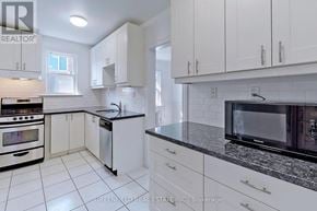 Toronto (Leaside) fourplex for rent - A kitchen with white cabinets and black appliances.