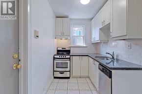 Toronto (Leaside) fourplex for rent - A kitchen with white cabinets and a black counter top.