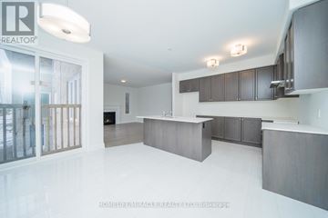 Oshawa (Samac) apartment for rent - A spacious kitchen with dark wood cabinets and a white countertop.