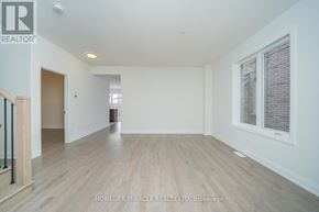 Oshawa (Samac) apartment for rent - A spacious room with wooden flooring and white walls, part of a real estate brokerage.