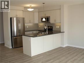 Kitchener townhouse for rent - A kitchen with white cabinets and a stainless steel refrigerator.