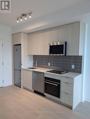 Toronto (Clairlea-Birchmount) condo for rent - A modern kitchen with a refrigerator, oven, and microwave.
