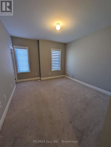 Clarington (Bowmanville) townhouse for rent - A room with a carpeted floor and two windows.