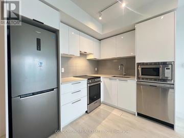 Toronto (Church-Yonge Corridor) condo for rent - A modern kitchen with stainless steel appliances and white cabinets.