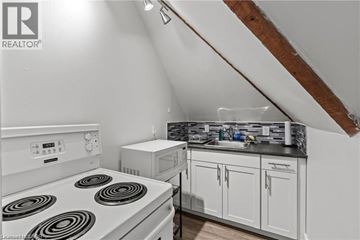 Hamilton apartment for rent - A white stove top oven in a kitchen with a microwave and a sink.