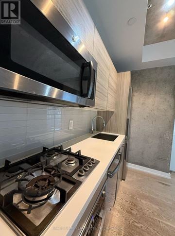 Toronto (Waterfront Communities) condo for rent - A modern kitchen with a stainless steel gas stove and a microwave above it.