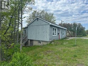 Parry Sound apartment for rent - A small, single-story house with a grey exterior is surrounded by greenery.