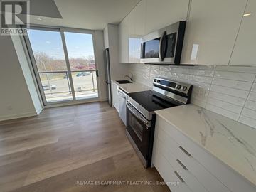 Brantford condo for rent - A kitchen with a stove top oven and microwave above it.