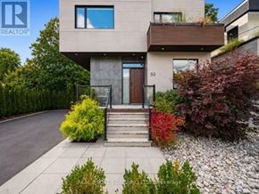 Toronto (High Park-Swansea) apartment for rent - A modern house with a brown door and windows is surrounded by greenery and a gravel path.