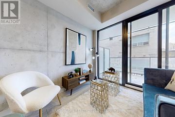 Toronto (Waterfront Communities) condo for rent - A modern living room with a white chair and a wooden side table.