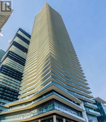 Toronto (Mimico) condo for rent - A tall building with a curved facade stands next to a shorter building with a striped pattern.