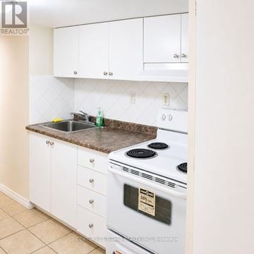 Markham (Cedarwood) townhouse for rent - A white stove with a black burner is in a kitchen with white cabinets.