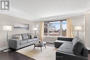 Hamilton (Stoney Creek) apartment for rent - A living room with a grey sofa, a coffee table, and a large window with curtains.