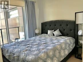Vancouver apartment for rent - A bed with a black headboard and a grey and white patterned duvet.