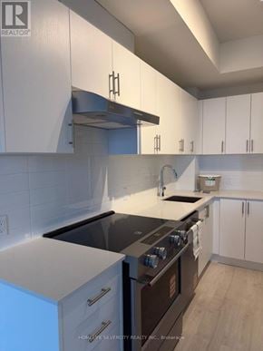 Vaughan (Vellore Village) condo for rent - A modern kitchen with white cabinets and a black stove top oven.