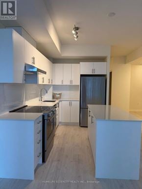Vaughan (Vellore Village) condo for rent - A modern kitchen with white cabinets and a black fridge.