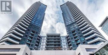 Markham (Thornhill) condo for rent - Two tall buildings with glass windows and a sign that reads "REALTOR® AMBER WORK REAL ESTATE".