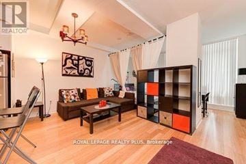 Mississauga (City Centre) condo for rent - A living room with a brown couch and a chandelier.