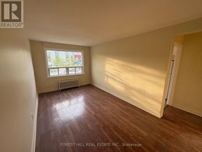 Mississauga (Port Credit) apartment for rent - A room with wooden flooring and a window showing a view of a building and trees.