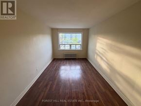 Mississauga (Port Credit) apartment for rent - A room with wooden floors and a window showing a view of trees and a building.