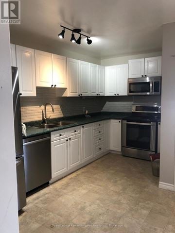 Kawartha Lakes (Lindsay) apartment for rent - A kitchen with white cabinets and a black fridge.