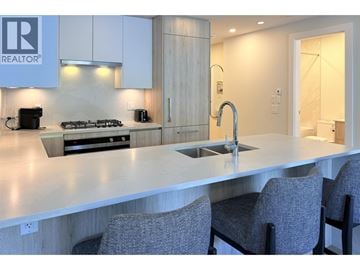 West Vancouver apartment for rent - A modern kitchen with a large island and grey chairs.