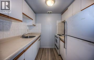 Kitchener townhouse for rent - A small, clean kitchen with white cabinets and a wooden floor.