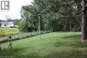 Kitchener townhouse for rent - Two children playing in a grassy area with trees and a fence in the background.