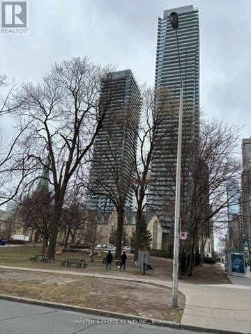 Toronto (Bay Street Corridor) condo for rent - A city street with a tall building in the background and a few people walking on the sidewalk.