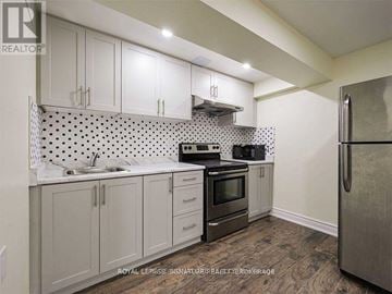 Mississauga (Central Erin Mills) apartment for rent - A kitchen with white cabinets and a black and white tiled backsplash.
