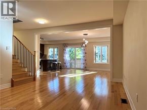 Niagara-On-The-Lake townhouse for rent - A spacious living room with wooden floors and a staircase leading to the upper level.