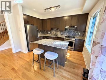 Niagara-On-The-Lake townhouse for rent - A kitchen with wooden cabinets and a granite countertop.