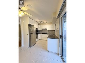 Vancouver apartment for rent - A modern kitchen with white cabinets and a stainless steel refrigerator.
