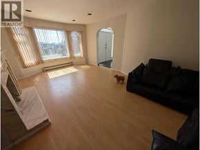 Vancouver apartment for rent - A dog is walking in a spacious living room with a couch and a staircase.