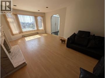 Vancouver apartment for rent - A dog is walking in a spacious living room with a couch and a staircase.