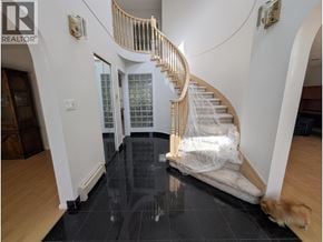Vancouver apartment for rent - A dog is standing on a black tiled floor in a house with a wooden staircase.