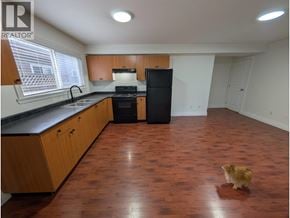 Richmond apartment for rent - A dog is standing in a kitchen with wooden floors and white walls.