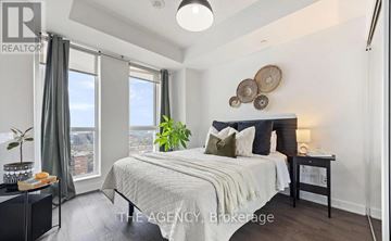 Toronto (Regent Park) condo for rent - A bedroom with a large bed and a view of the city.
